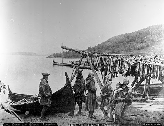 Sjøssamer med båt. I bakgrunn fiskehjell.