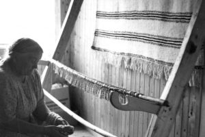 Anne H. Blomsterli klipper grenen løs fra veven.
Foto: Marta Hoffmann, Norsk Folkemuseum