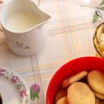 KJøkkenbord med småkaker, skål med sukkerbiter, kopp med kaffe, skål med melk.