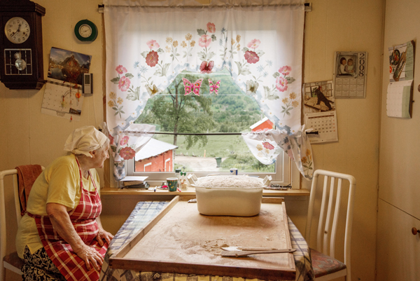 Oliva baker 12 brød. Brøddeig til heving på kjøkkenbodet. Oliva titter ut av kjøkkenvinduet.