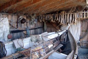 Naust med båt og tørrfisk.