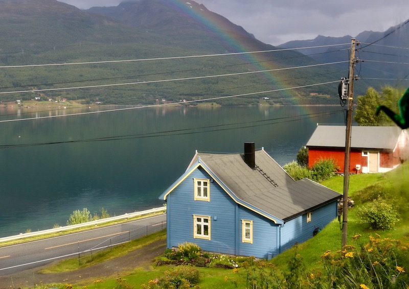 Regnbue over blått hus i kulturlandskap Skardalen